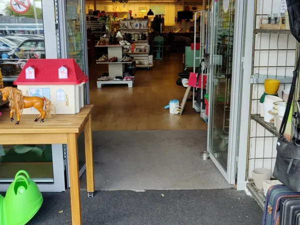 Winkelvloer van een kringloopwinkel met speelgoed, huishoudartikelen en diverse gebruikte goederen uitgestald.