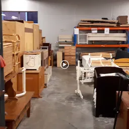 Magazijnruimte met houten meubels, pianoklavierturen en dozen op rekken