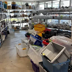 Winkelvloer met plastic opbergbakken, stellingen met dozen en diverse spullen langs de wanden