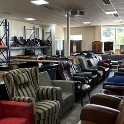 Uitgestalde tweedehands fauteuils en stoelen in verschillende kleuren en stijlen in de winkel