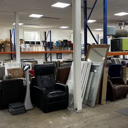 Winkelvloer met diverse meubels zoals fauteuils, stoelen en kasten in een kringloopwinkel