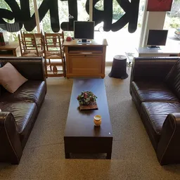 Woonkamer met twee bruine leren banken, salontafel en houten stoelen in kringloopwinkel