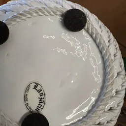 Close-up van wit servies met decoratief randje en touwgreep, mogelijk een schaal of kom