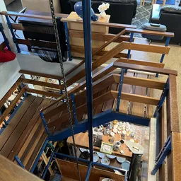 Kringloopwinkelinterieur met houten stellingen, blauwe bracing, en diverse tweedehands huisraad en servies op planken