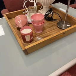 Roze kaarsen en huishoudartikelen op houten dienblad