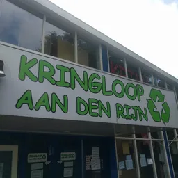 Gevel van kringloopwinkel met groene letters 'KRINGLOOP AAN DEN RIJN' en recyclesymbool
