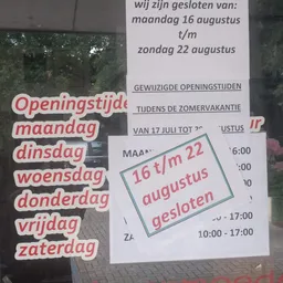 Openingstijden en gesloten perioden van een kringloopwinkel op een wit bord