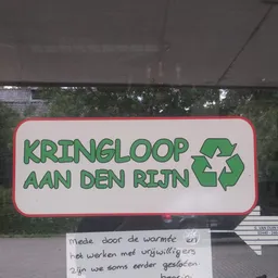 Uithangbord met groen logo en recyclesymbool van kringloopwinkel aan den rijn