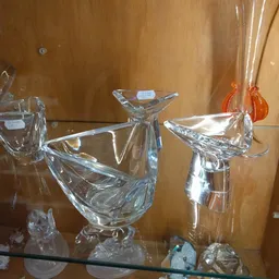 Glazen decoratieve voorwerpen en beeldjes in een vitrinekasten, waaronder kristallen vogels en vazen