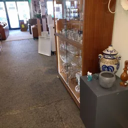 Vitrinekast met serviesgoed en decoratieve items zoals aardewerk, kandelaars en een blauwe decoratieve pot.