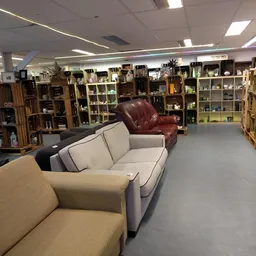 Winkelvloer met meubels zoals banken en fauteuils, op de achtergrond stellingen met diverse huishoudartikelen en decoratie