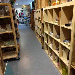 Wintelpad tussen houten stellingen met diverse artikelen in kastjes in een kringloopwinkel