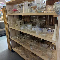 Glazenkast met verschillende kristallen glazen, vazen en decoratieve artikelen uitgestald op meerdere legels