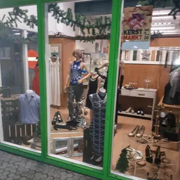 Winkelinterieur met kledingrekken, mannequins en schoenen op display