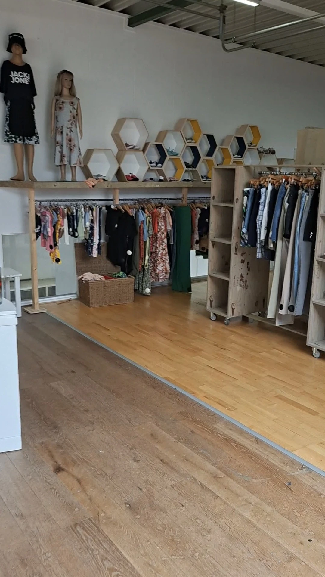 Winkelinterieur met kledingrekken vol tweedehands kleding, houten vloer en stellingen
