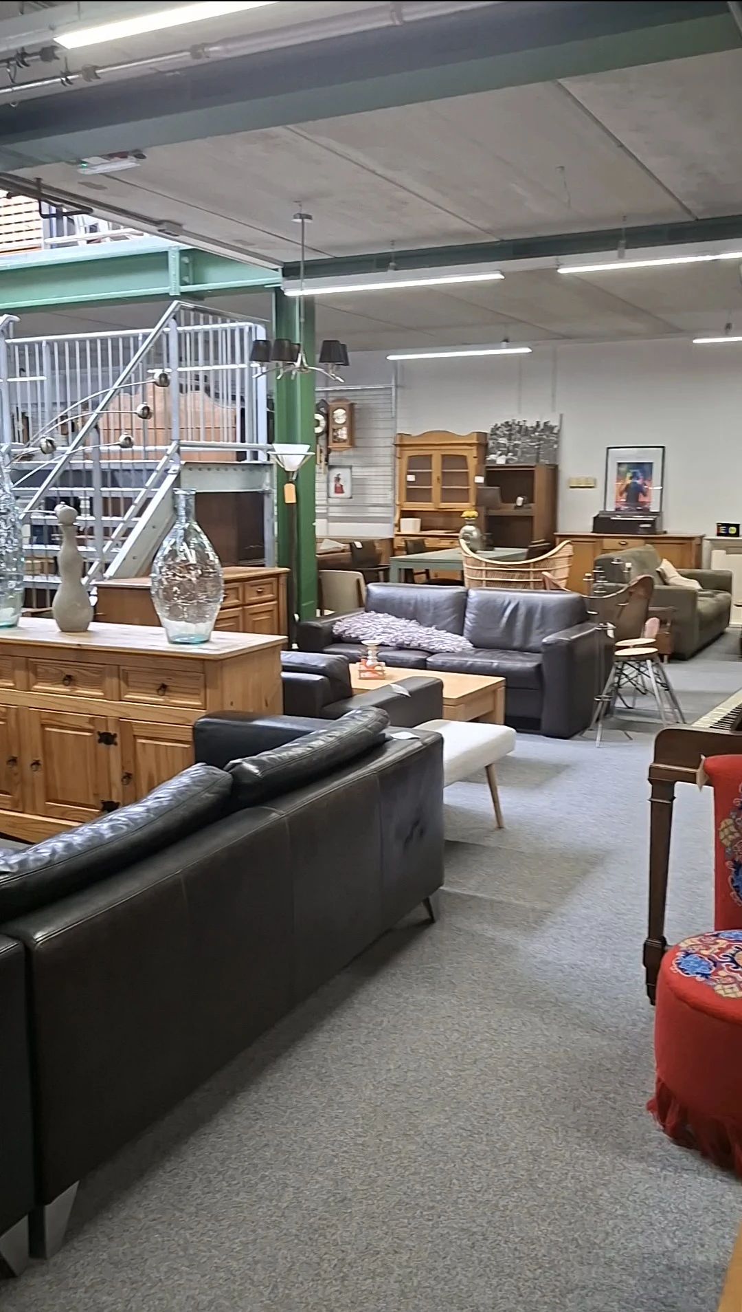 Winkelvloer met meubels: zithoeken met grijze banken, houten kasten, tafels en decoratieve objecten