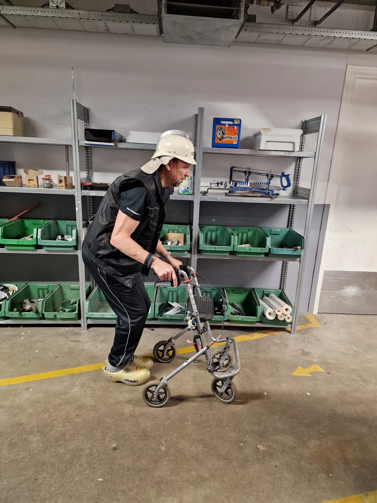 Medewerker in witte helm en zwart vest demonstreert een tweewielig voertuig in de winkel met groene stellingkasten op de acht