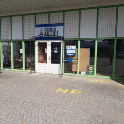Voorgevel van Kringloop Aktief met groene raamkozijnen, witte deur en winkelnaam op bord boven ingang