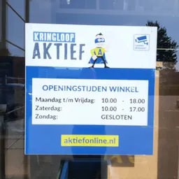 Winkelraam met blauwe bord met openingstijden: maandag t/m vrijdag 10.00-18.00, zaterdag 10.00-17.00, zondag gesloten