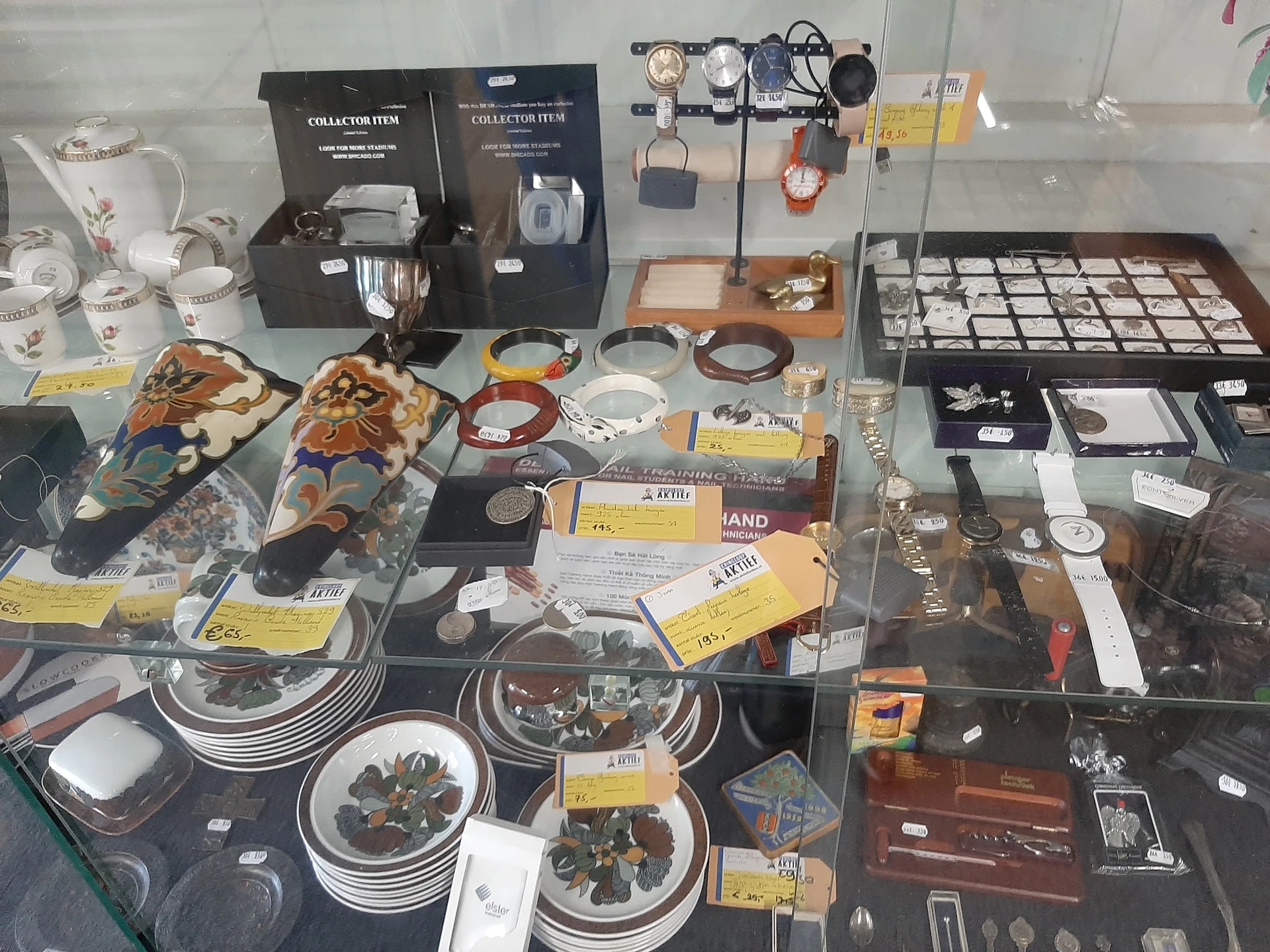 Vitrinekast met uitgestalde vintage voorwerpen: servies, horloges, sieraden, collectibles en huishoudartikelen