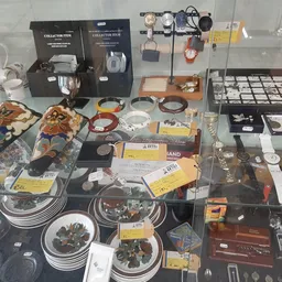 Vitrinekast met uitgestalde vintage voorwerpen: servies, horloges, sieraden, collectibles en huishoudartikelen