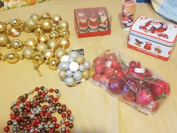 Uitgestalde kerstversiering en decoraties op een tafel: gouden en rode ballen, slingers, kaarsen en kerstdoosjes