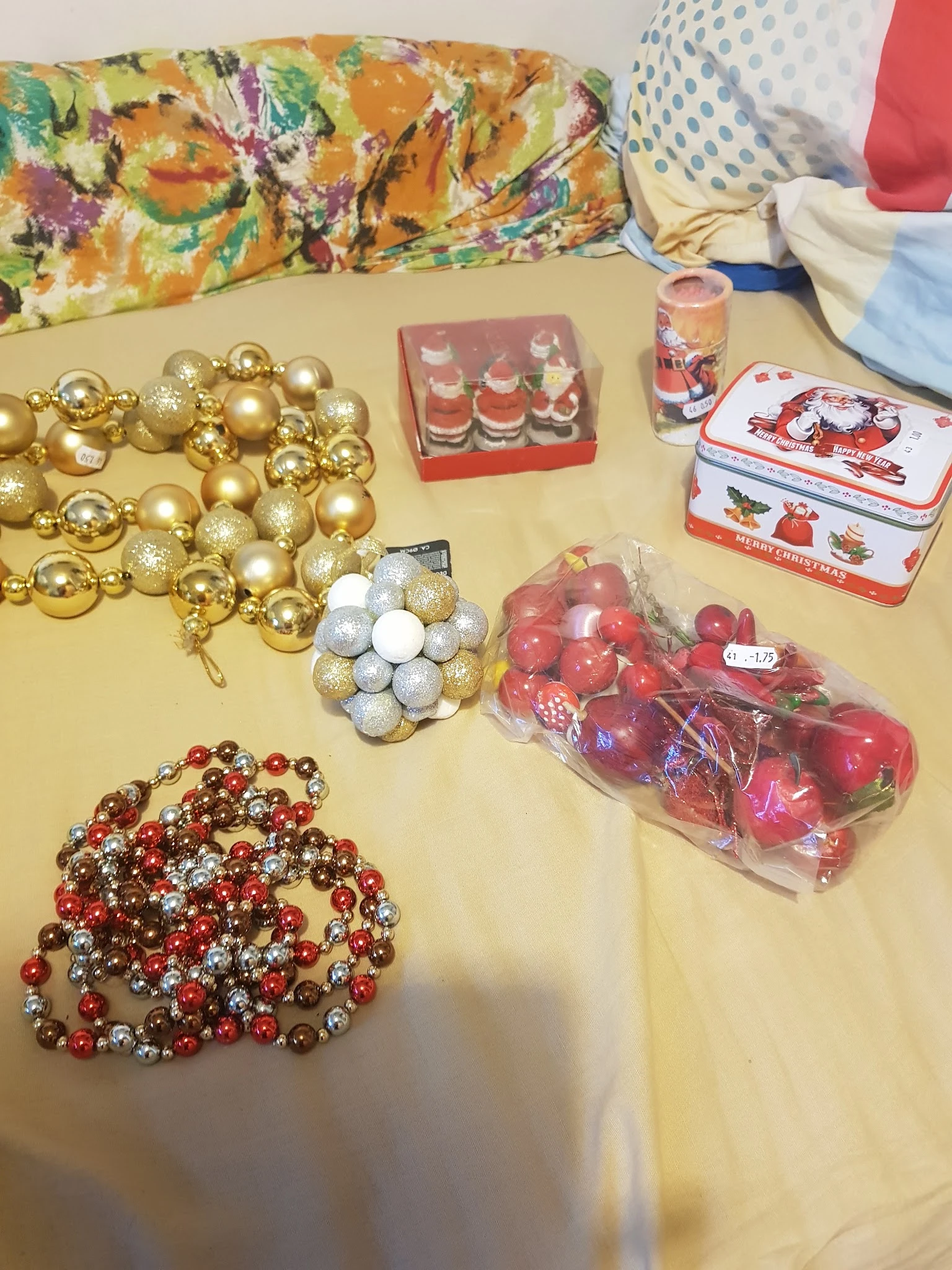 Uitgestalde kerstversiering en decoraties op een tafel: gouden en rode ballen, slingers, kaarsen en kerstdoosjes