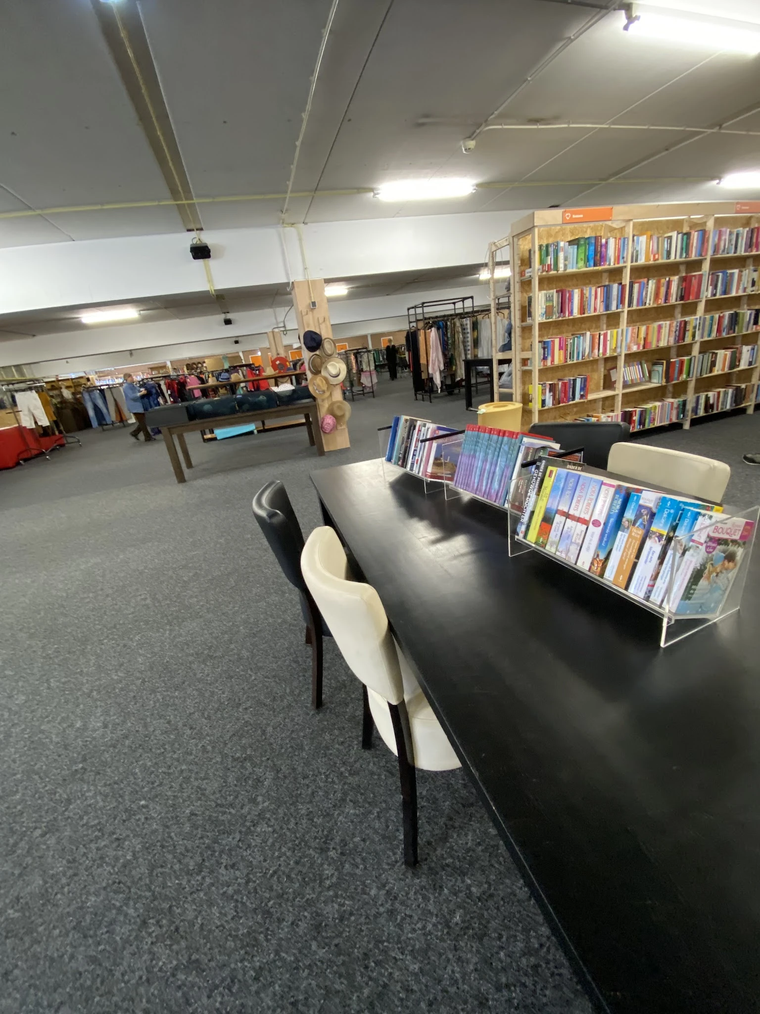 Winkelvloer met zwarte tafel, boeken in rekken, boekenkasten op de achtergrond en diverse spullen