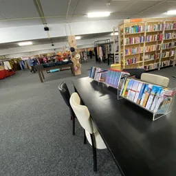 Winkelvloer met zwarte tafel, boeken in rekken, boekenkasten op de achtergrond en diverse spullen