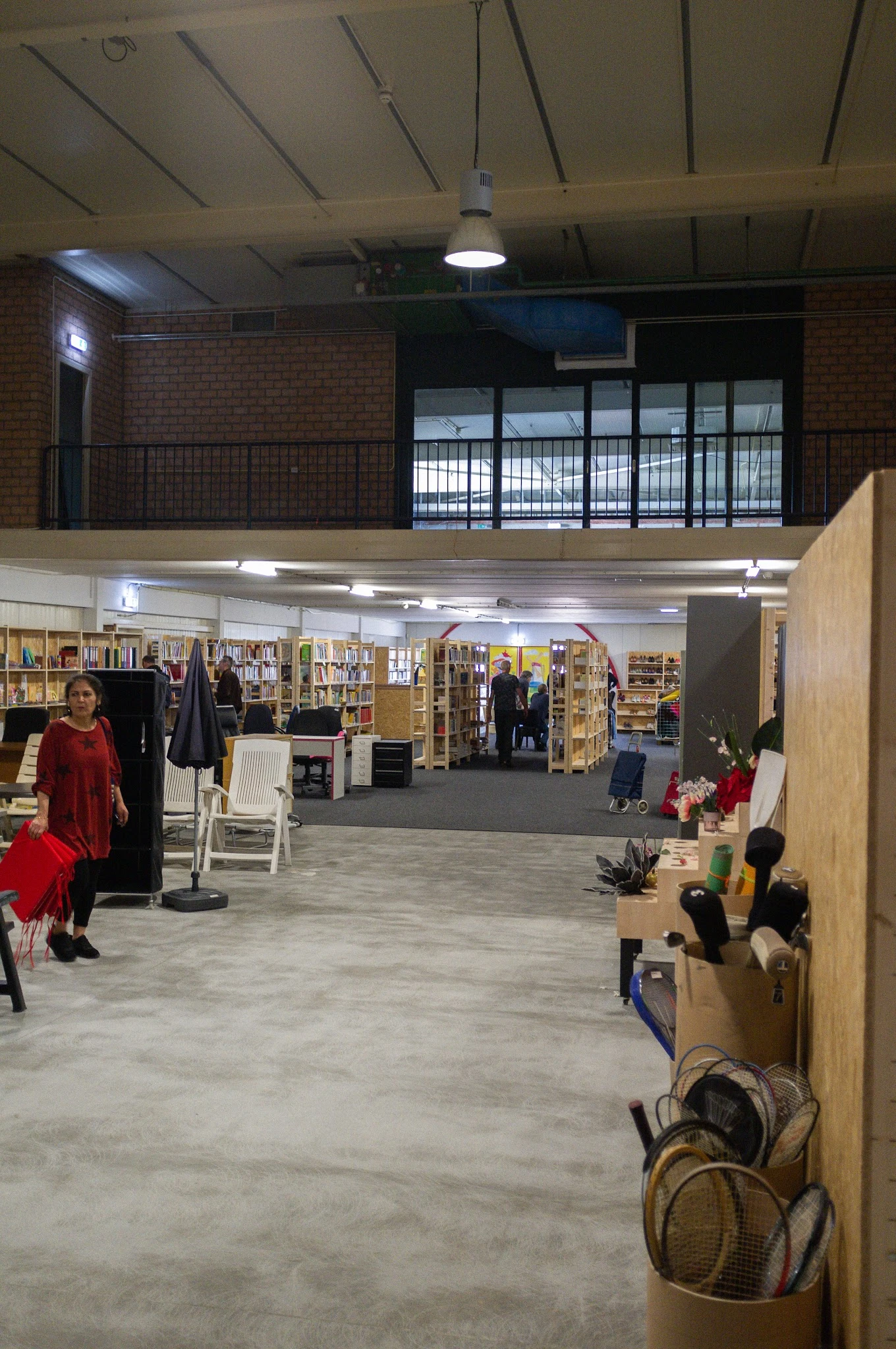 Overzicht van de winkelvloer met boekenrekken, kledingrekken en diverse spullen in een ruim magazijnachtig pand