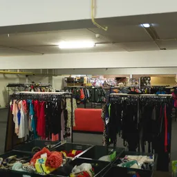 Rekken met tweedehands kleding in verschillende kleuren, voornamelijk zwart, rood en blauw