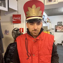Man met rode vest en gouden carnavalstooi in de winkel