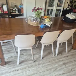 Houten eettafel met witte stoelen en bloemenvaas op het tafelblad