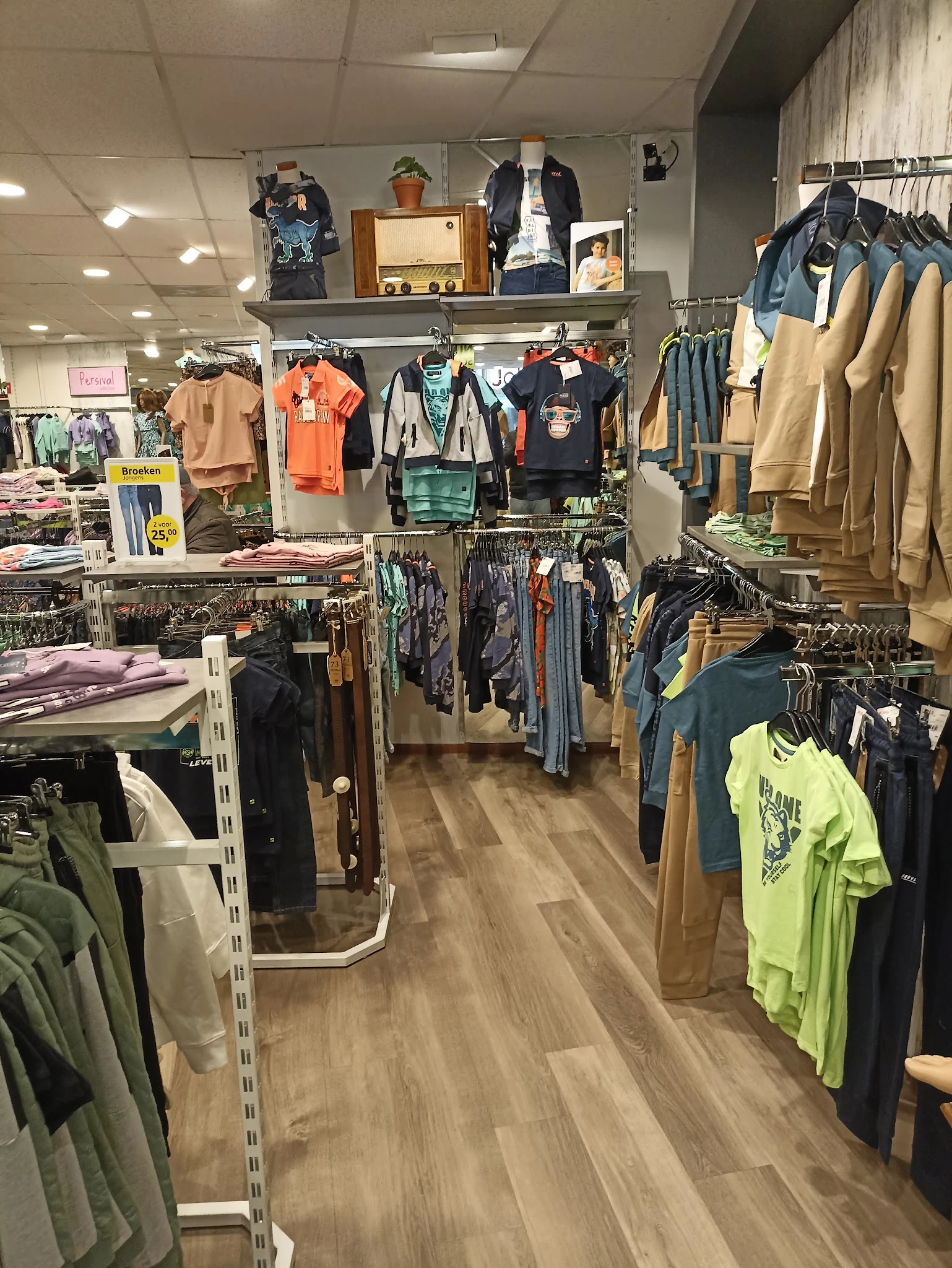 Winkelvloer met rekken vol kleding, overzicht van kledingafdeling met diverse artikelen