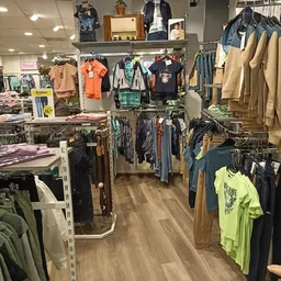 Winkelvloer met rekken vol kleding, overzicht van kledingafdeling met diverse artikelen