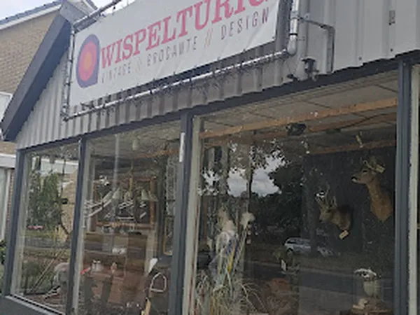 Wispelturig Design kringloopwinkel met glazen pui en rood logo op gevel