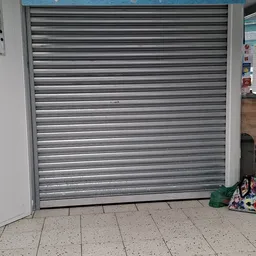 Gesloten metalen rolluik van een winkel met enkele voorwerpen op de grond