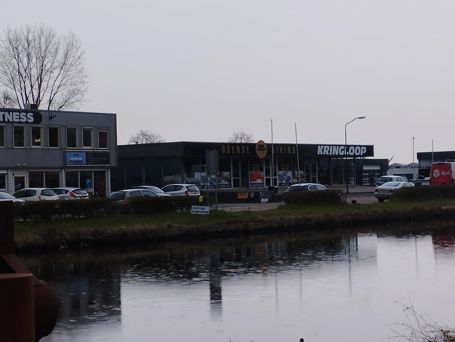 Winkelgevel aan water met parkeerplaats en enkele auto's ervoor