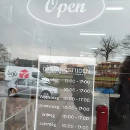 Winkelraam met openingstijden en bedrijfsbus zichtbaar