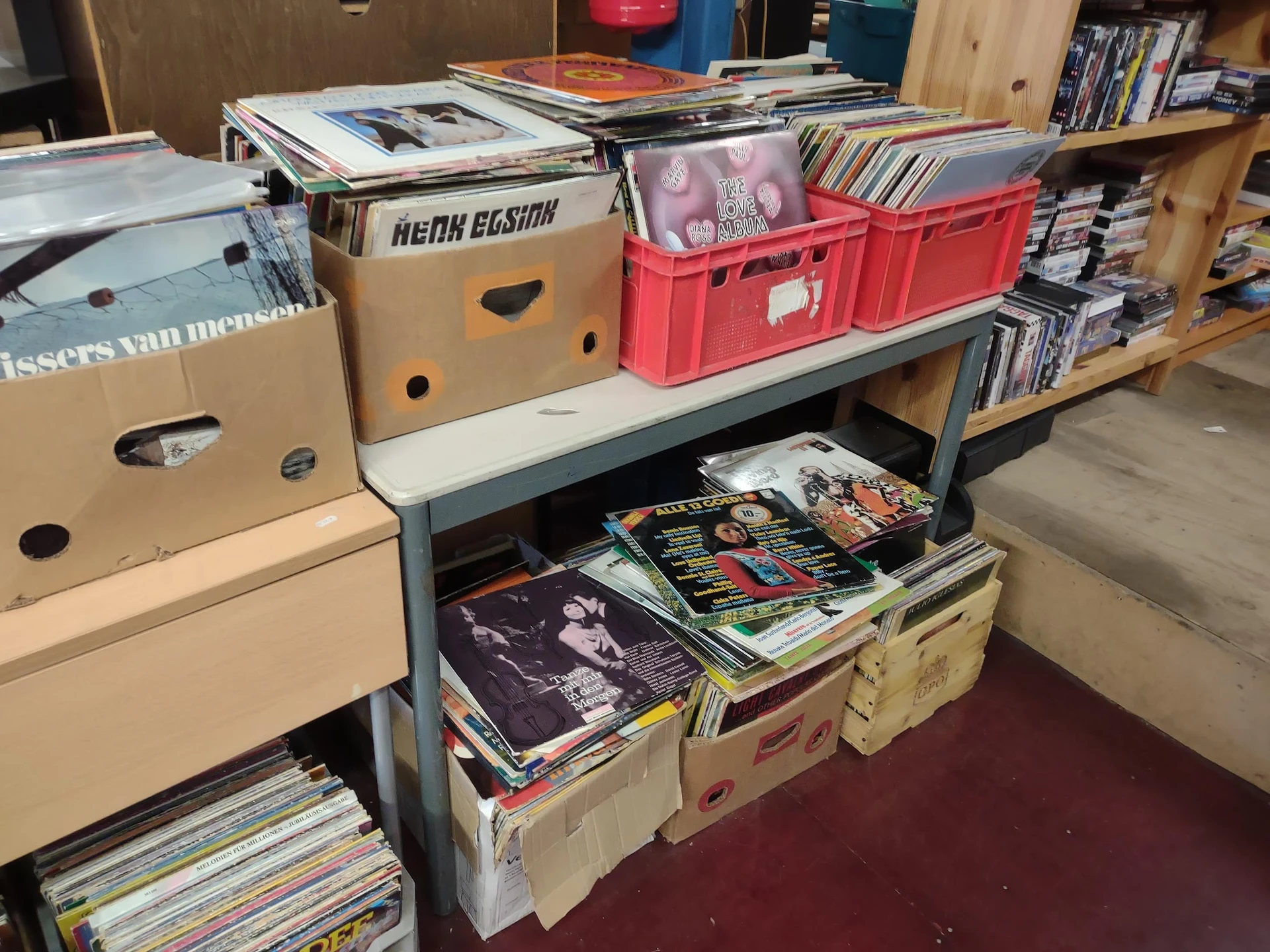 Stellingen met dozen en bakken vol cd's, dvd's en andere media's in de kringloopwinkel