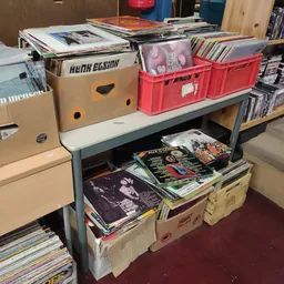 Stellingen met dozen en bakken vol cd's, dvd's en andere media's in de kringloopwinkel