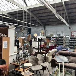 Winkelinterieur met zithoeken, meubels en diverse inrichtingsartikelen onder industrieel plafond