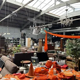 Magazijnruimte met vintage meubels, kroonluchters, decoratieve items en oranje versieringen