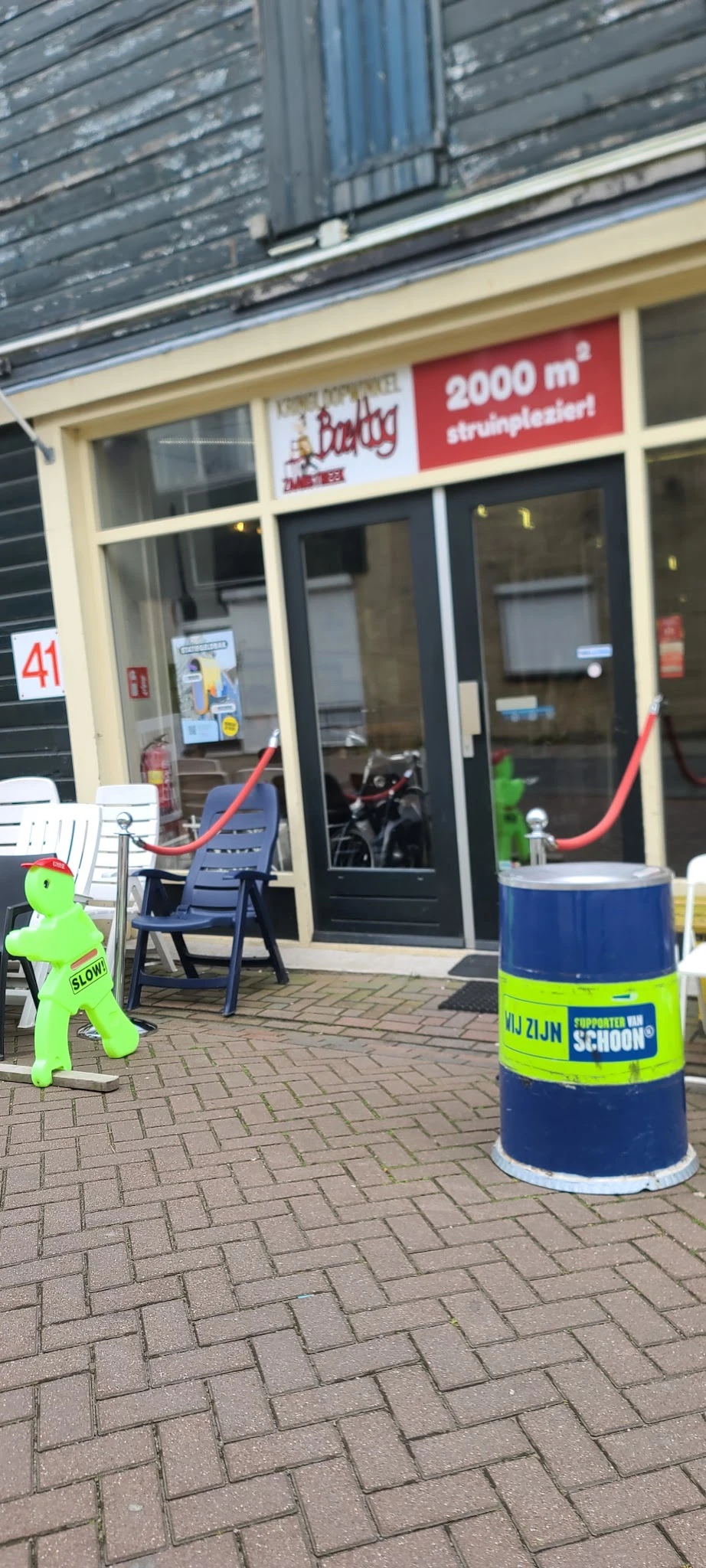 Winkelvoorgevel met glazen deuren, blauwe stoelen op terras en groenig decoratiemateriaal