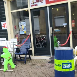 Winkelvoorgevel met glazen deuren, blauwe stoelen op terras en groenig decoratiemateriaal