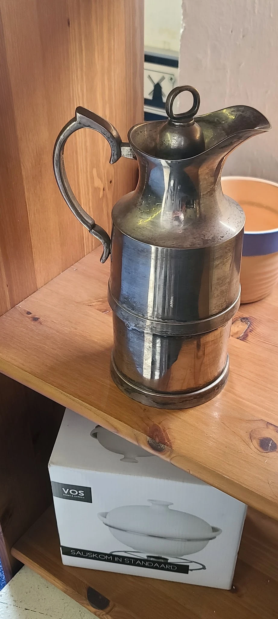Vintage metalen melkkan met twee compartimenten en zwart handvat op houten tafel