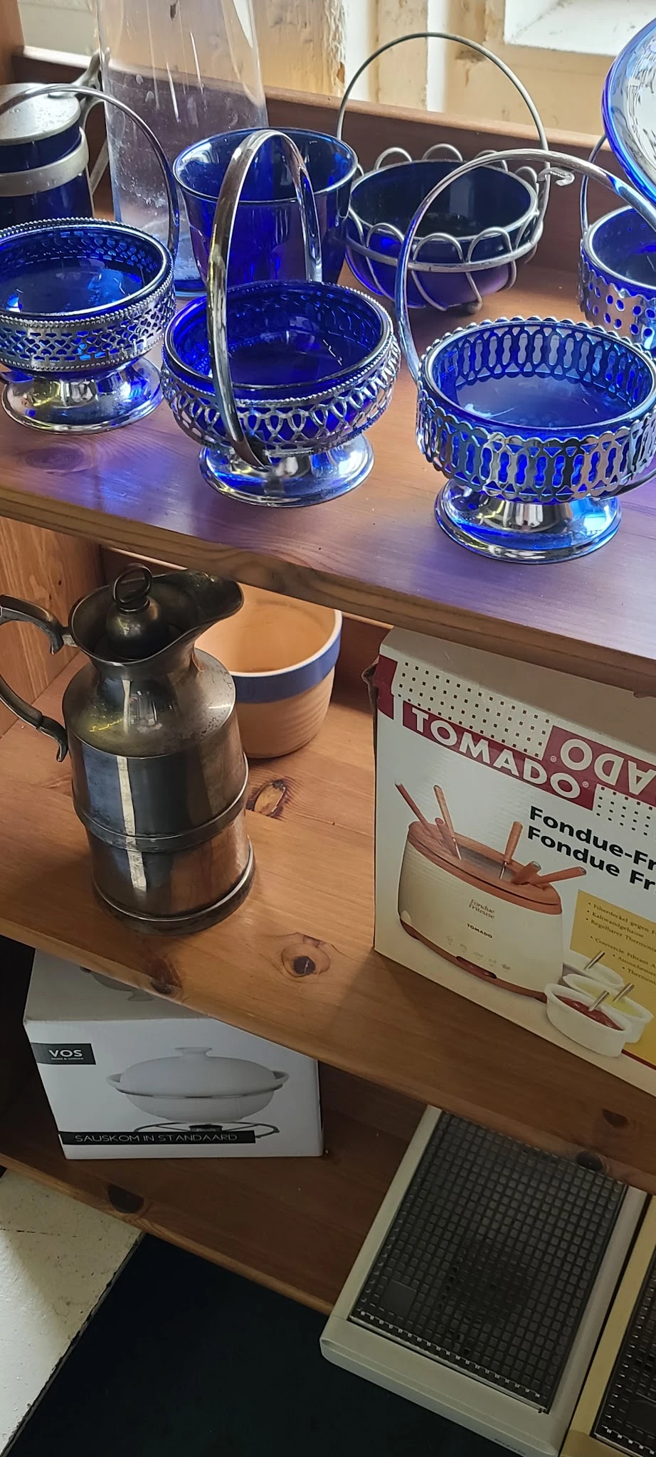 Zwarte thermoskan met dop naast een beige-blauwe doos op houten tafel