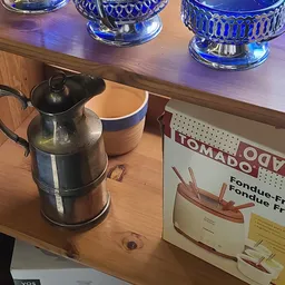 Zwarte thermoskan met dop naast een beige-blauwe doos op houten tafel