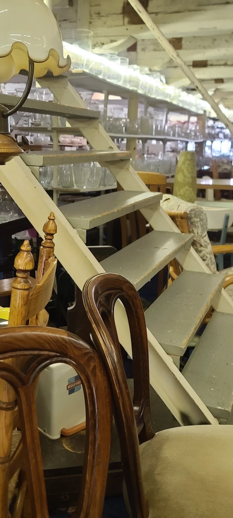 Houten stoel met bruinen zitting en gebogen rugleuning, met houten finials op achtergrond