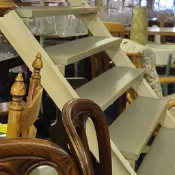 Houten stoel met bruinen zitting en gebogen rugleuning, met houten finials op achtergrond